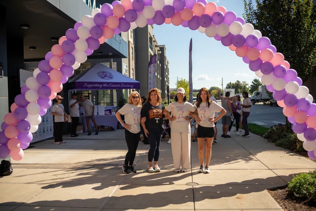 Walkers posing together under the purple and pink balloon arch