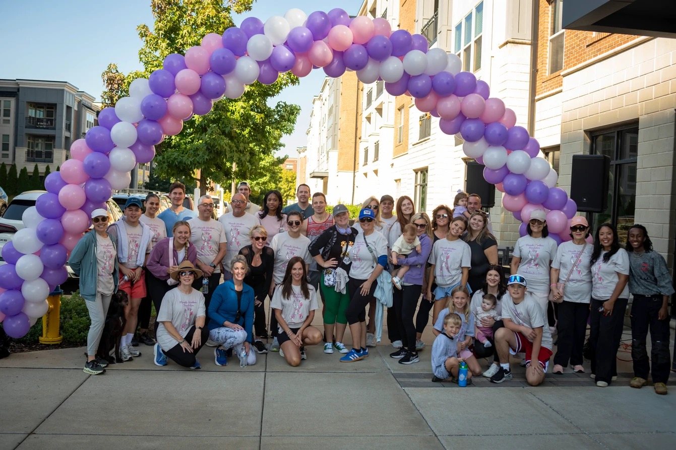 A large group of participants gathered under the balloon arch at the 2025 walk